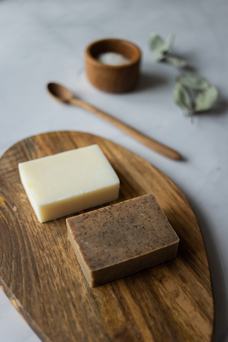 Handmade soap prepared on wooden board near organic scrub